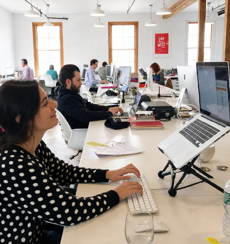 Imigital team members working at their desks in a bright open-plan studio